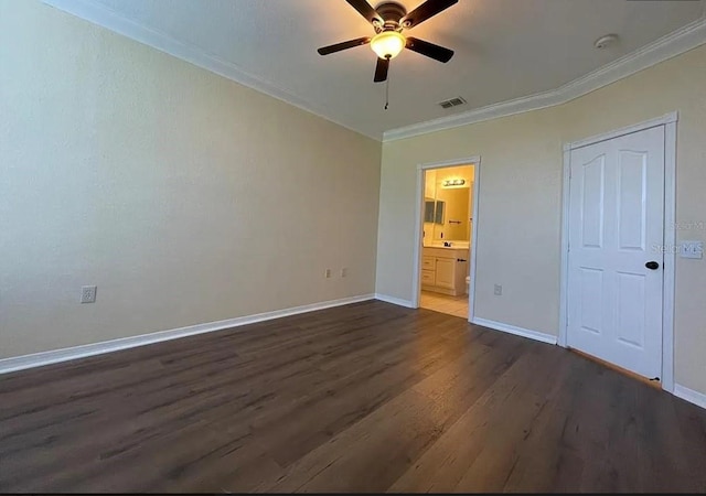 unfurnished bedroom featuring ornamental molding, dark wood-type flooring, ensuite bath, and ceiling fan