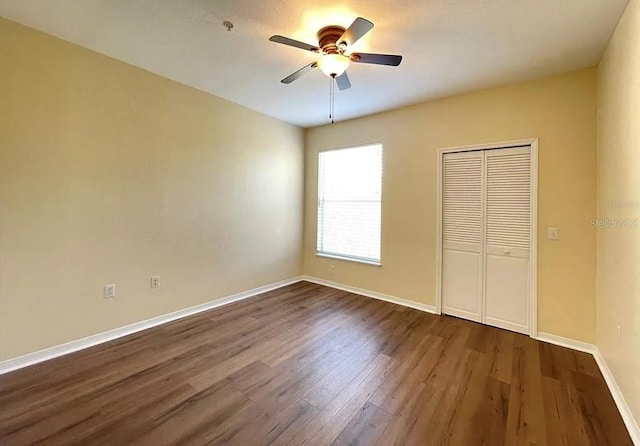 unfurnished bedroom featuring dark wood-type flooring, ceiling fan, and a closet