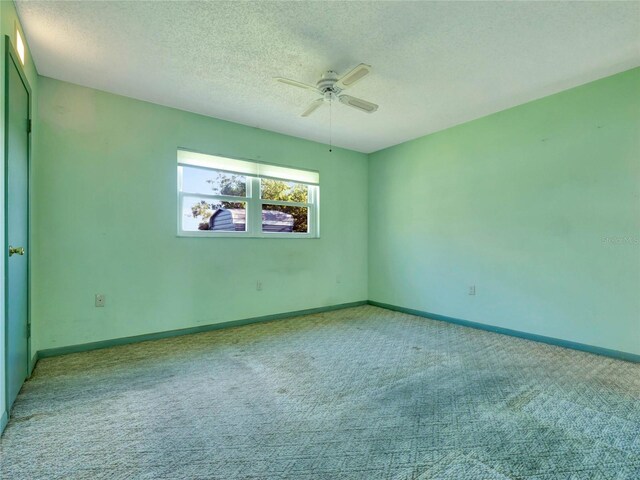 spare room with ceiling fan, a textured ceiling, and light carpet