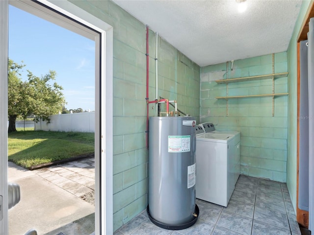 washroom featuring washing machine and clothes dryer, a textured ceiling, and electric water heater