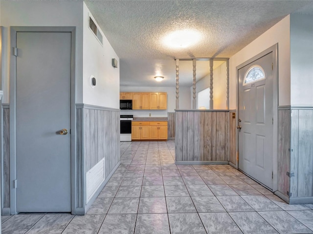 kitchen with a textured ceiling, white range oven, and light brown cabinets