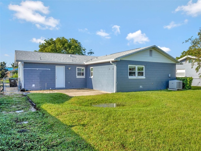 rear view of property featuring central air condition unit, a lawn, and a patio