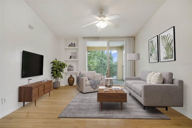 living area with ceiling fan, baseboards, built in shelves, and light wood-style flooring