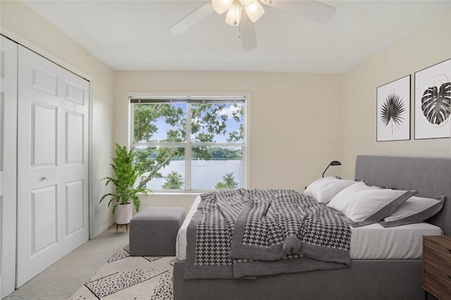 bedroom with a closet, ceiling fan, and light carpet