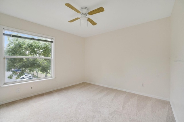 unfurnished room featuring baseboards, light colored carpet, and ceiling fan