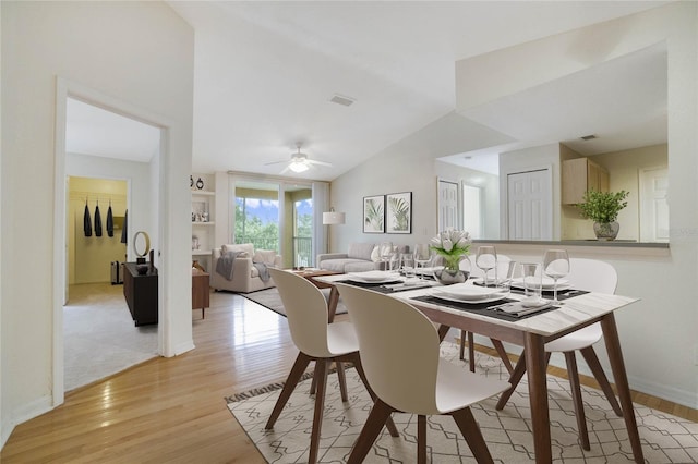 dining area featuring visible vents, baseboards, lofted ceiling, light wood-style flooring, and a ceiling fan
