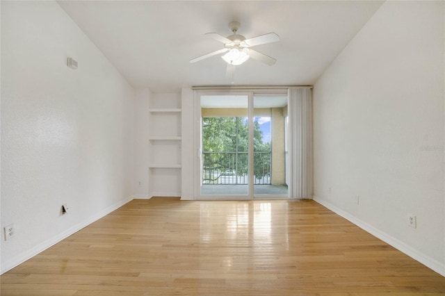 unfurnished room featuring ceiling fan, built in shelves, and light wood-type flooring