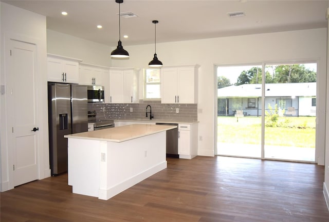 kitchen with white cabinetry, decorative light fixtures, a center island, stainless steel appliances, and decorative backsplash