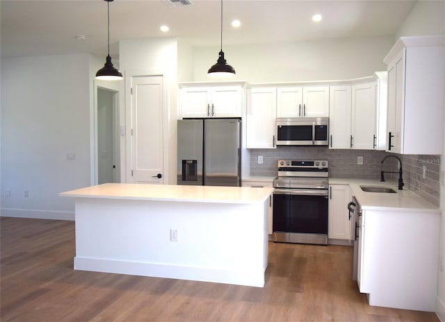 kitchen with sink, a kitchen island, white cabinets, and appliances with stainless steel finishes