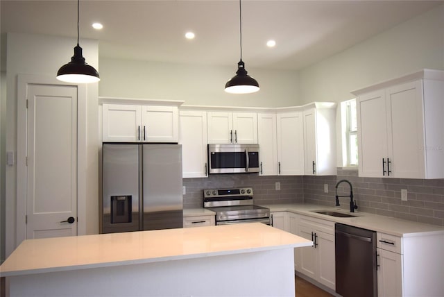 kitchen featuring white cabinetry, stainless steel appliances, sink, and hanging light fixtures