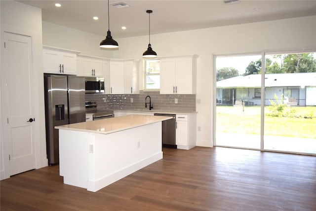 kitchen with stainless steel appliances, white cabinetry, a kitchen island, and sink