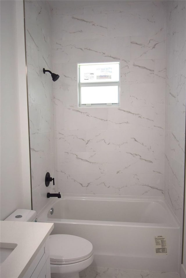 full bathroom featuring vanity, tiled shower / bath, and toilet