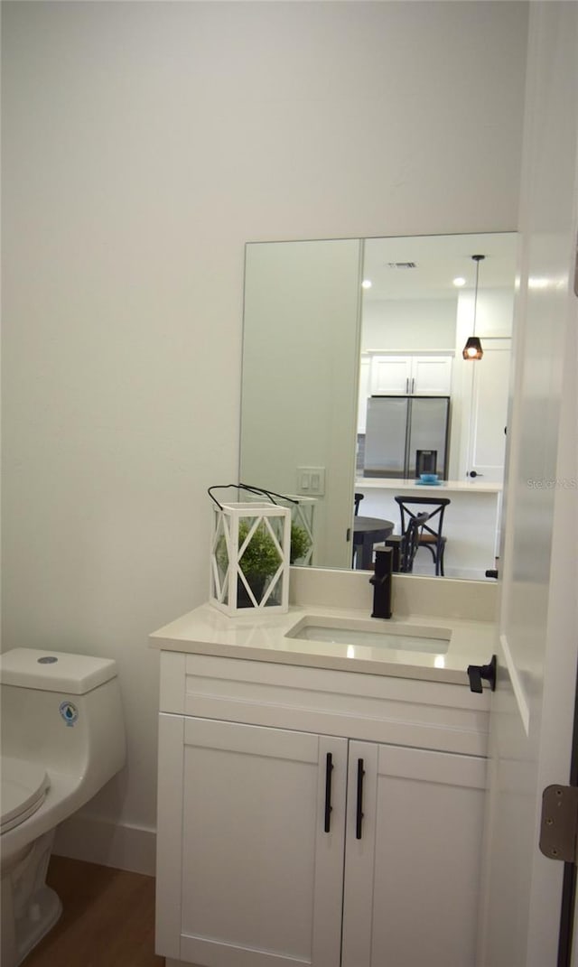 bathroom with vanity, toilet, and hardwood / wood-style floors