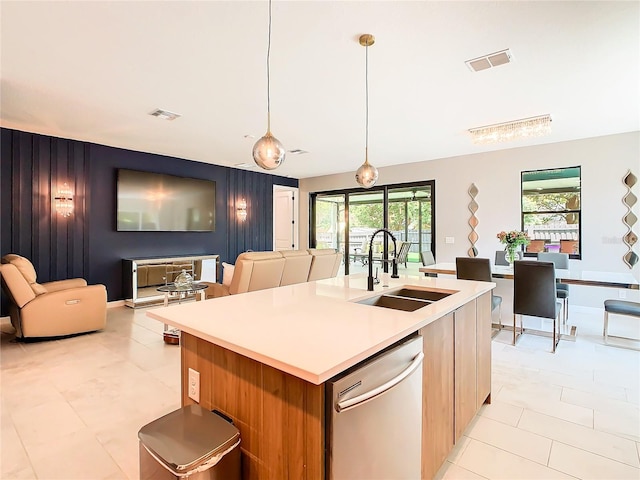 kitchen featuring dishwasher, a kitchen island with sink, light tile patterned floors, and hanging light fixtures