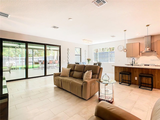 living room with a wealth of natural light, light tile patterned flooring, and sink