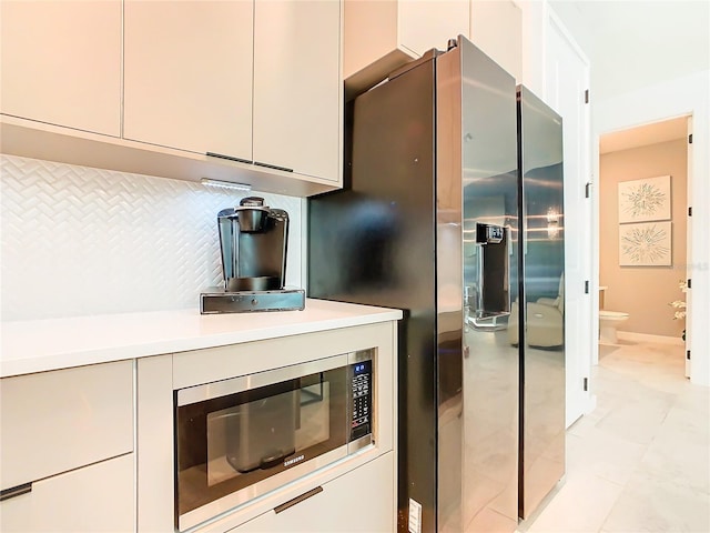 kitchen with light tile patterned floors, stainless steel microwave, and decorative backsplash