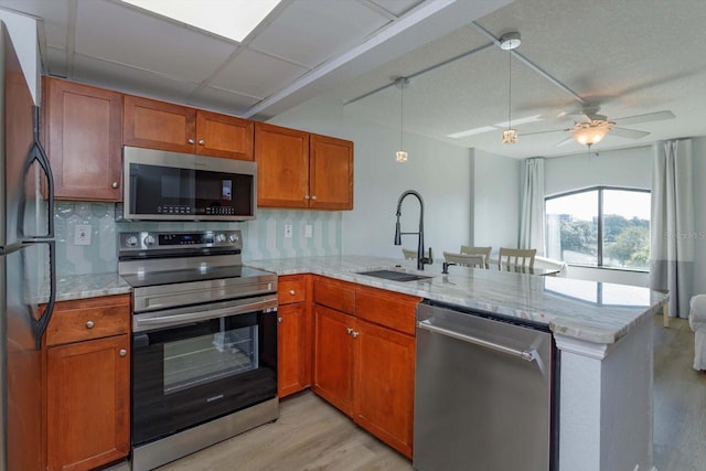 kitchen featuring ceiling fan, stainless steel appliances, kitchen peninsula, and sink