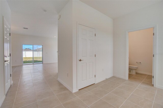 hall featuring light tile patterned floors and baseboards