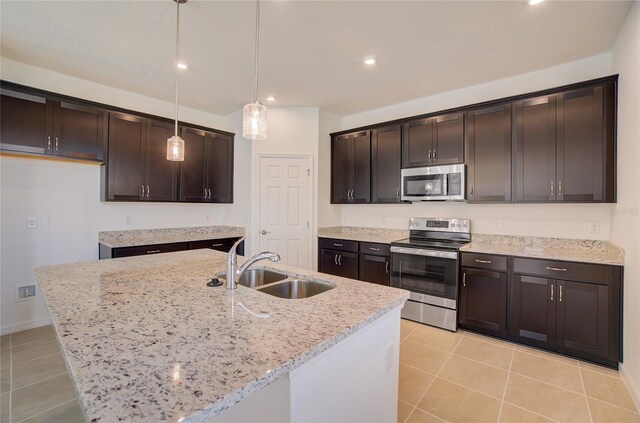 kitchen with stainless steel appliances, pendant lighting, a sink, and an island with sink