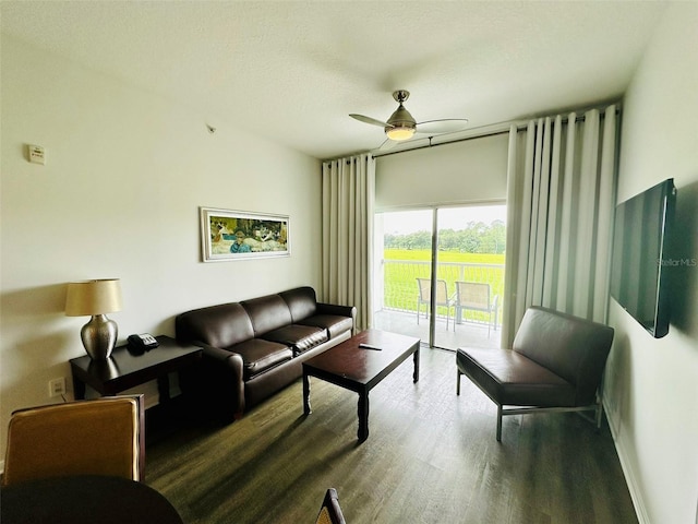 living room with a ceiling fan, dark wood-style flooring, and a textured ceiling