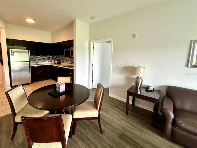 dining area with a textured ceiling, light wood-type flooring, and baseboards