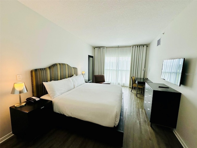 bedroom with baseboards, a textured ceiling, visible vents, and dark wood-style flooring