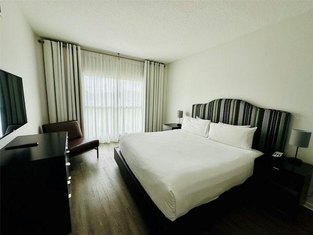 bedroom with a textured ceiling and dark wood-type flooring