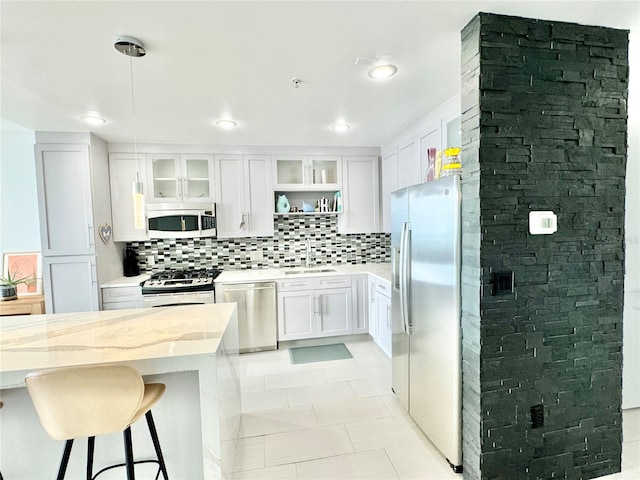 kitchen featuring sink, stainless steel appliances, white cabinets, and decorative light fixtures