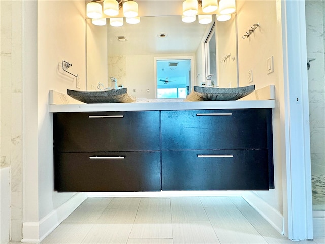 bathroom with tile patterned floors, an inviting chandelier, and vanity