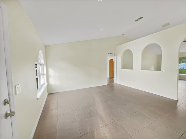 empty room with vaulted ceiling and light tile patterned floors