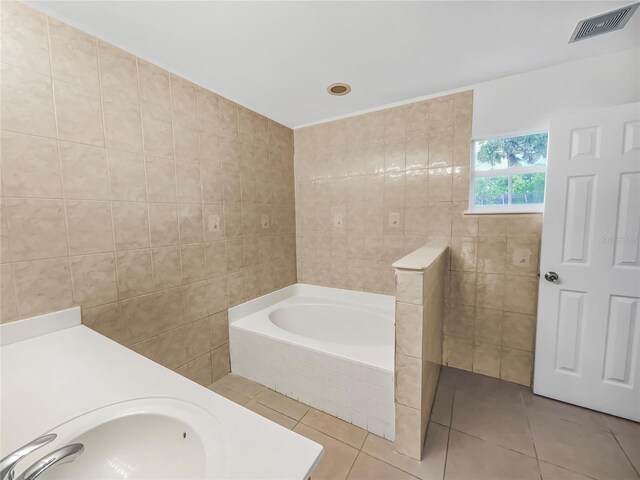 bathroom featuring sink, tile patterned floors, tiled tub, and tile walls