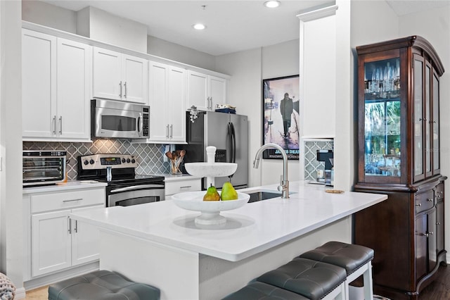 kitchen with a kitchen breakfast bar, white cabinetry, and appliances with stainless steel finishes