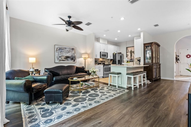 living room featuring ceiling fan and dark wood-type flooring