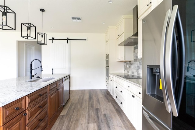 kitchen featuring appliances with stainless steel finishes, dark hardwood / wood-style floors, white cabinetry, hanging light fixtures, and wall chimney range hood