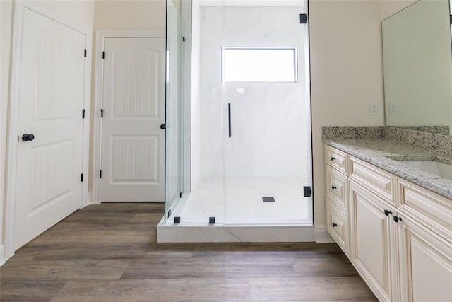 bathroom featuring wood-type flooring, vanity, and a shower with shower door