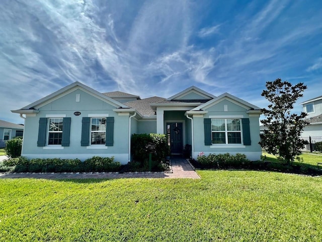 ranch-style house featuring a front lawn and stucco siding