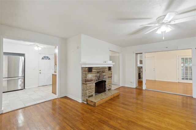 unfurnished living room featuring a fireplace, ceiling fan, and light wood-type flooring