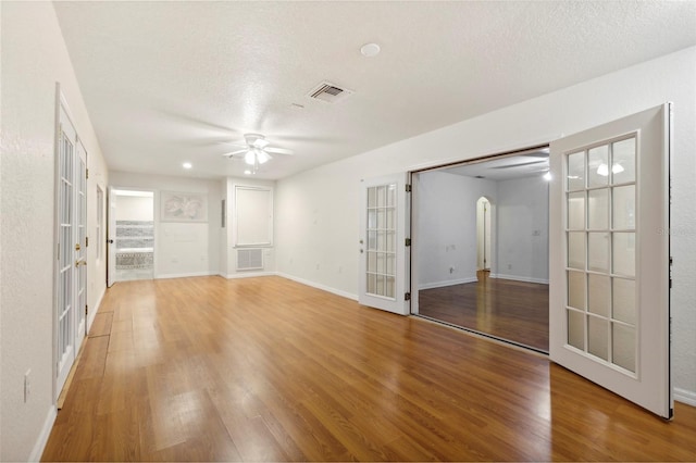 interior space featuring a textured ceiling, ceiling fan, hardwood / wood-style floors, and french doors