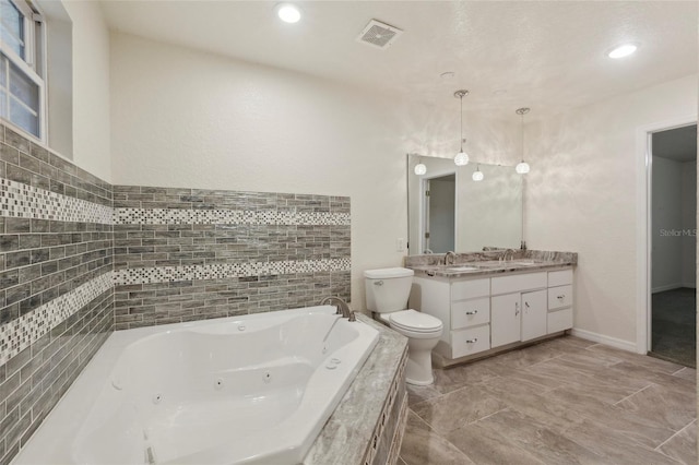 bathroom with tiled tub, vanity, tile patterned floors, tile walls, and toilet