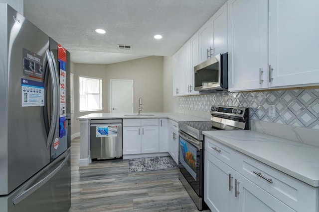 kitchen featuring white cabinetry, tasteful backsplash, light hardwood / wood-style flooring, stainless steel appliances, and sink