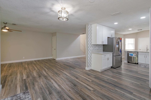 kitchen featuring a textured ceiling, hardwood / wood-style floors, appliances with stainless steel finishes, and white cabinetry