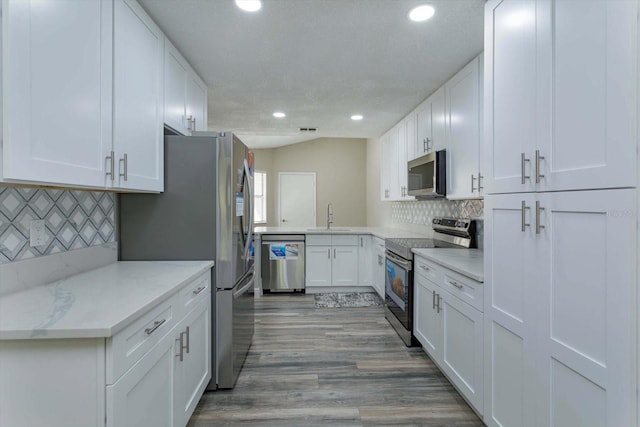 kitchen featuring light hardwood / wood-style flooring, appliances with stainless steel finishes, white cabinets, and decorative backsplash