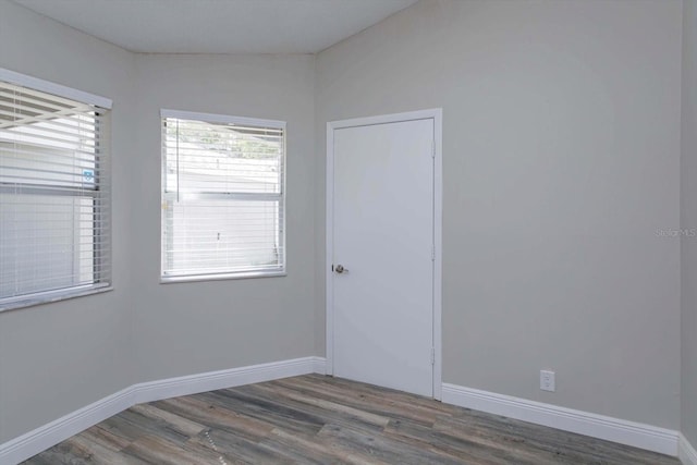 spare room featuring lofted ceiling and hardwood / wood-style floors