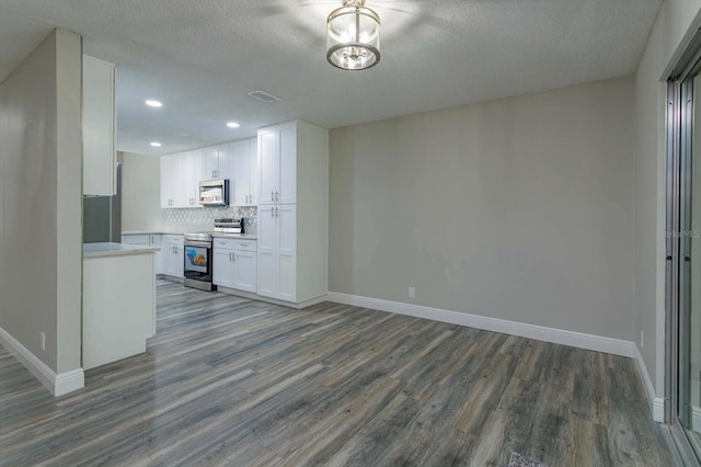 kitchen featuring hardwood / wood-style floors, white cabinetry, tasteful backsplash, a textured ceiling, and appliances with stainless steel finishes