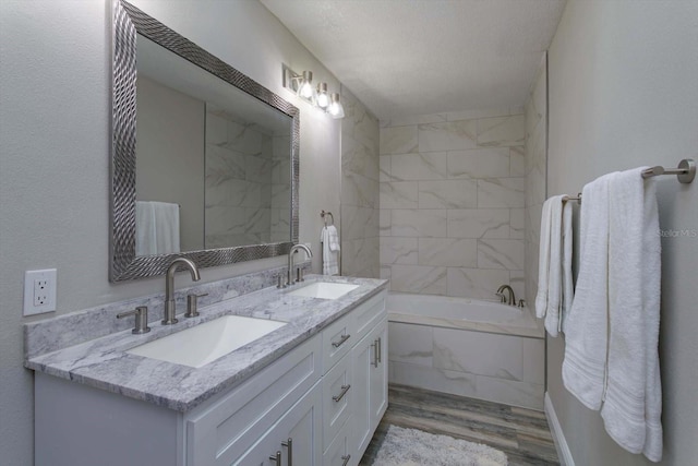 bathroom with hardwood / wood-style floors, a bathtub, a textured ceiling, and vanity