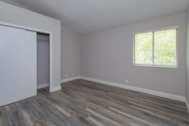 unfurnished bedroom with dark wood-type flooring, a closet, and a textured ceiling