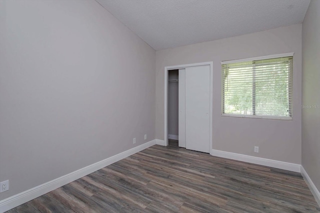 unfurnished bedroom featuring vaulted ceiling, dark hardwood / wood-style flooring, and a textured ceiling