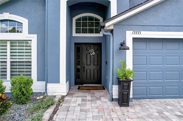 property entrance featuring a garage and stucco siding