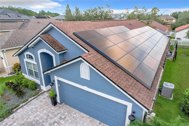 view of front facade featuring a garage, solar panels, and central AC