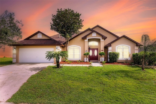 single story home with concrete driveway, a lawn, an attached garage, and stucco siding